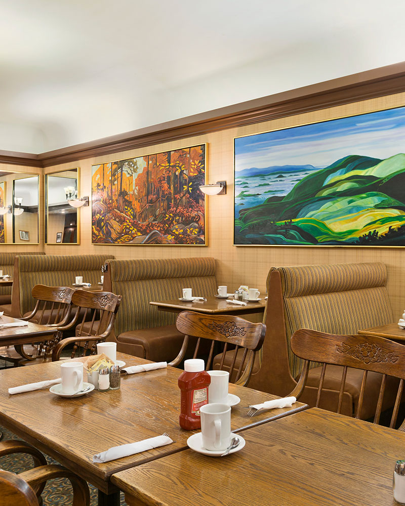 Chelsea's Restaurant at Days Inn Vancouver Downtown has leather booths and square dining tables set with white coffee mugs and cutlery wrapped in white napkins.